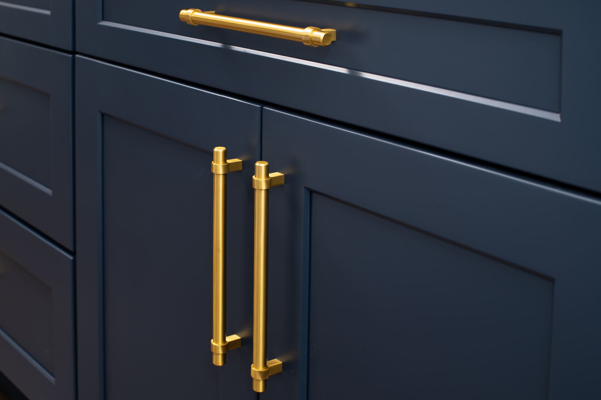 Gold hardware on navy blue kitchen cabinets with modern handles and knobs