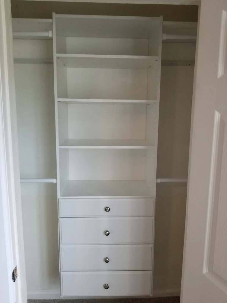 White built-in closet shelving unit with four drawers and open shelves