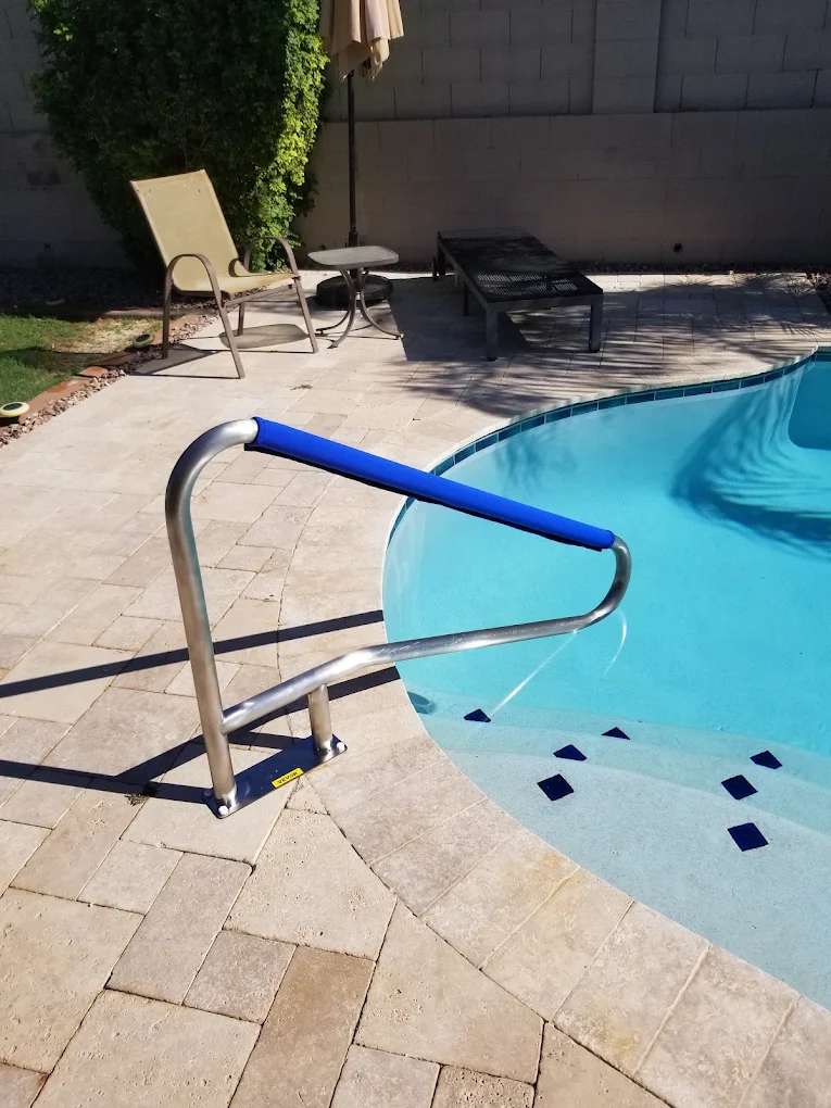 Pool handrail with blue foam cover at edge of backyard swimming pool