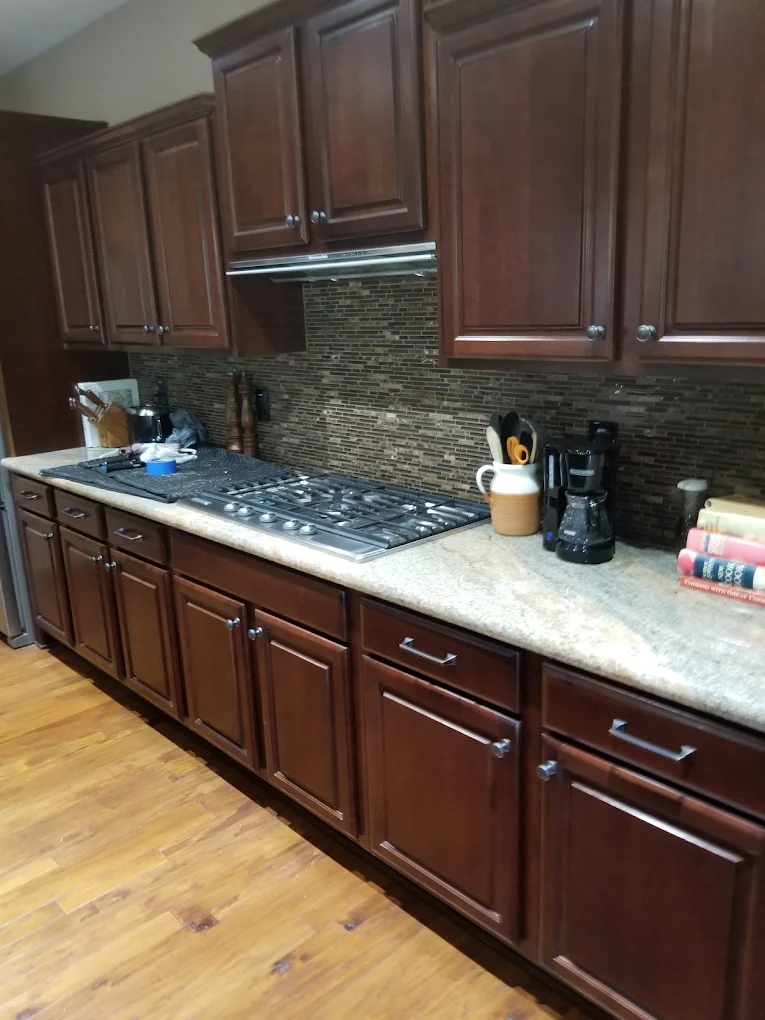 Modern kitchen with dark cherry cabinets, gray countertops, and gray tile backsplash