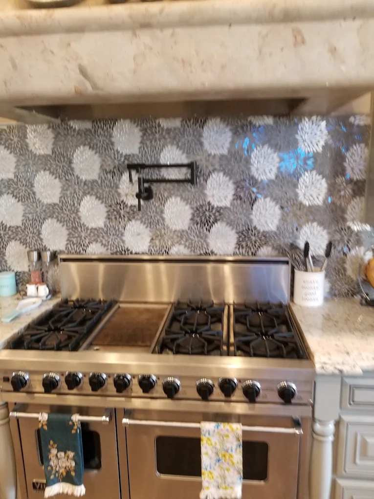Stainless steel dual oven gas range with six burners and griddle in modern kitchen with patterned backsplash