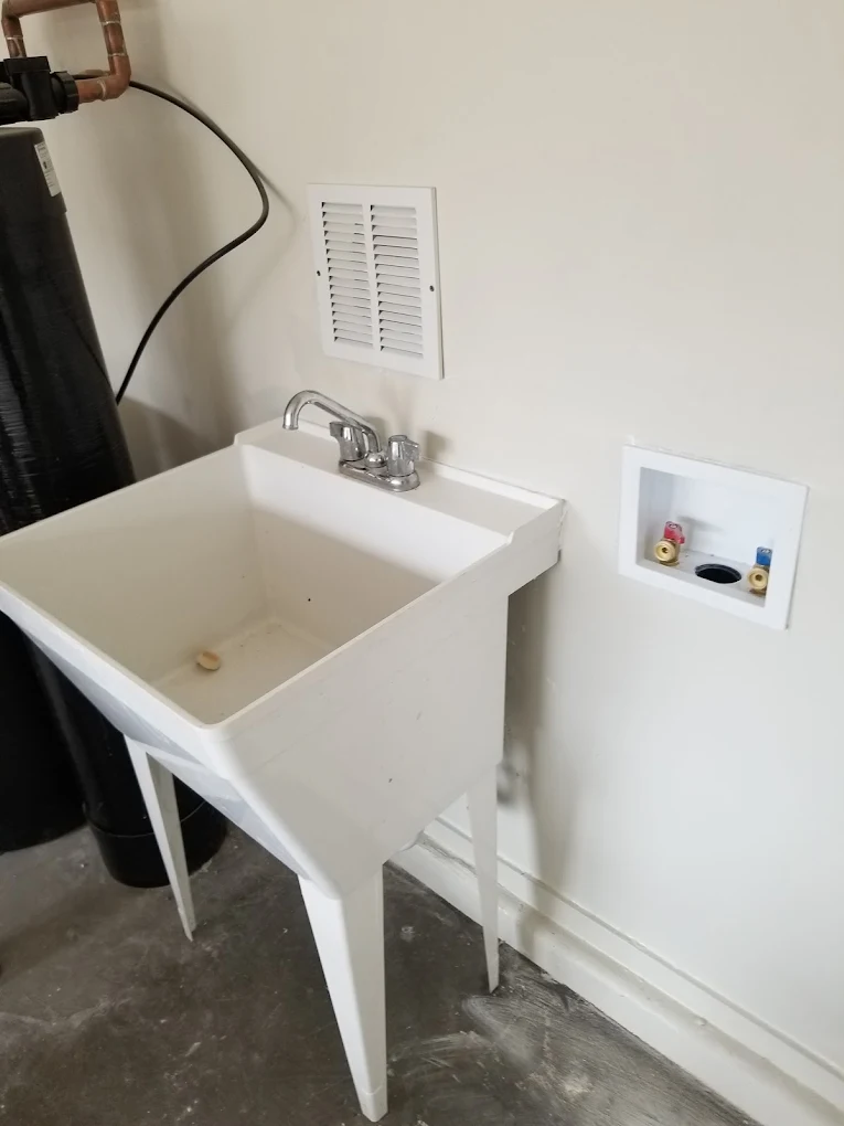 White utility sink with faucet and drain hose in laundry room