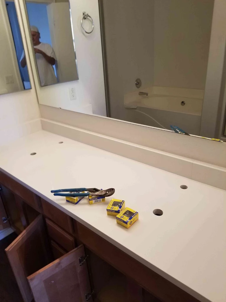 Bathroom vanity with sink, mirror, and countertop displaying tools and supplies