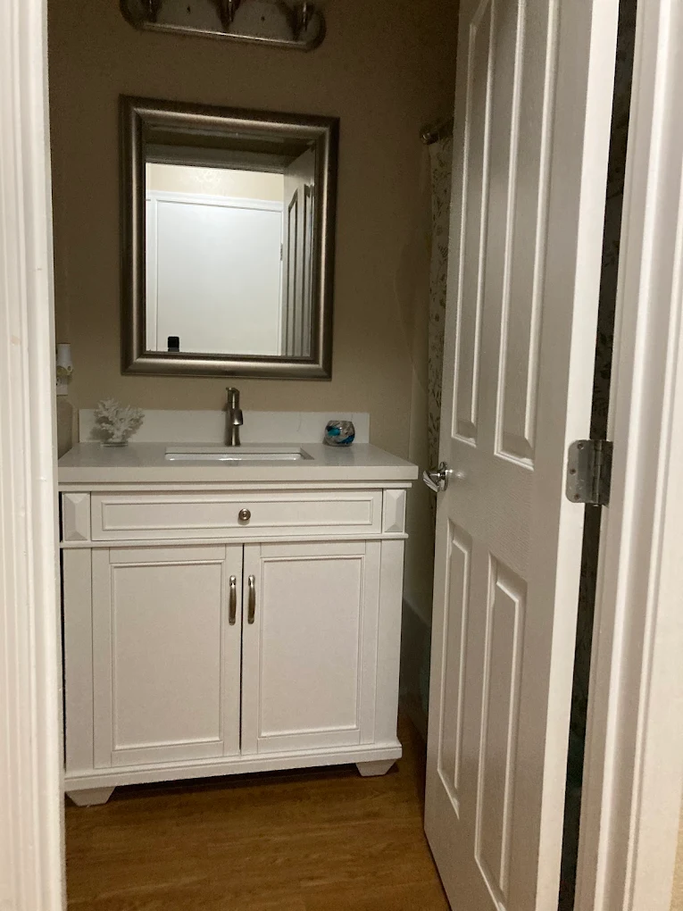 Modern bathroom vanity with white cabinetry, sink, and framed mirror above quartz countertop