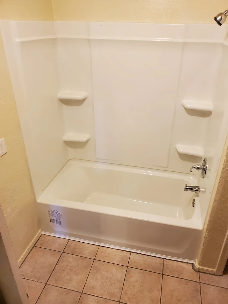 White bathtub and surround with built-in shelves and tile flooring