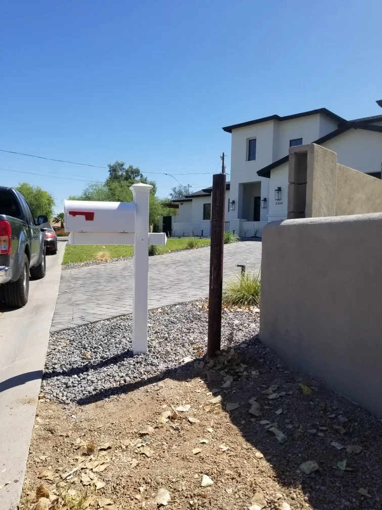 Modern residential home with white mailbox and gated driveway on paved street