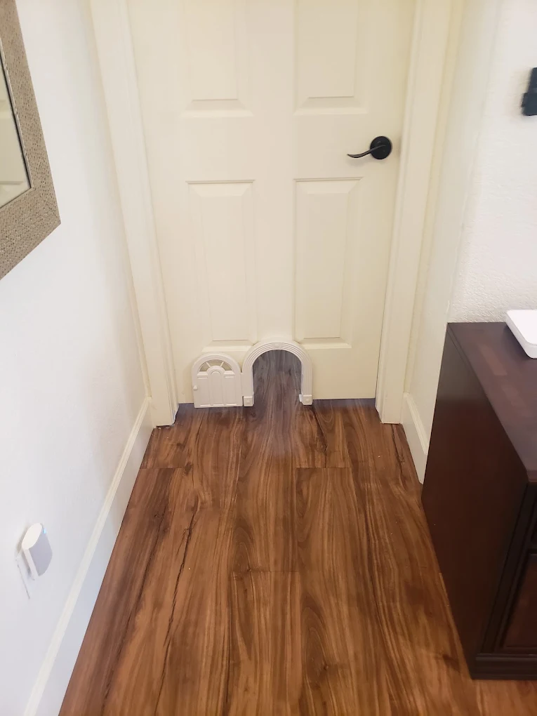 Cream-colored six-panel interior door with black handle in hallway with wood flooring