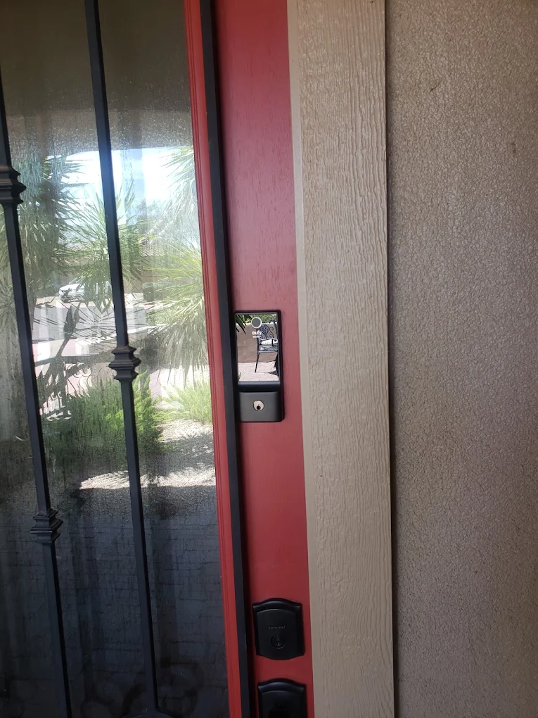 Red door frame with black handles and electronic keypad lock beside textured wall
