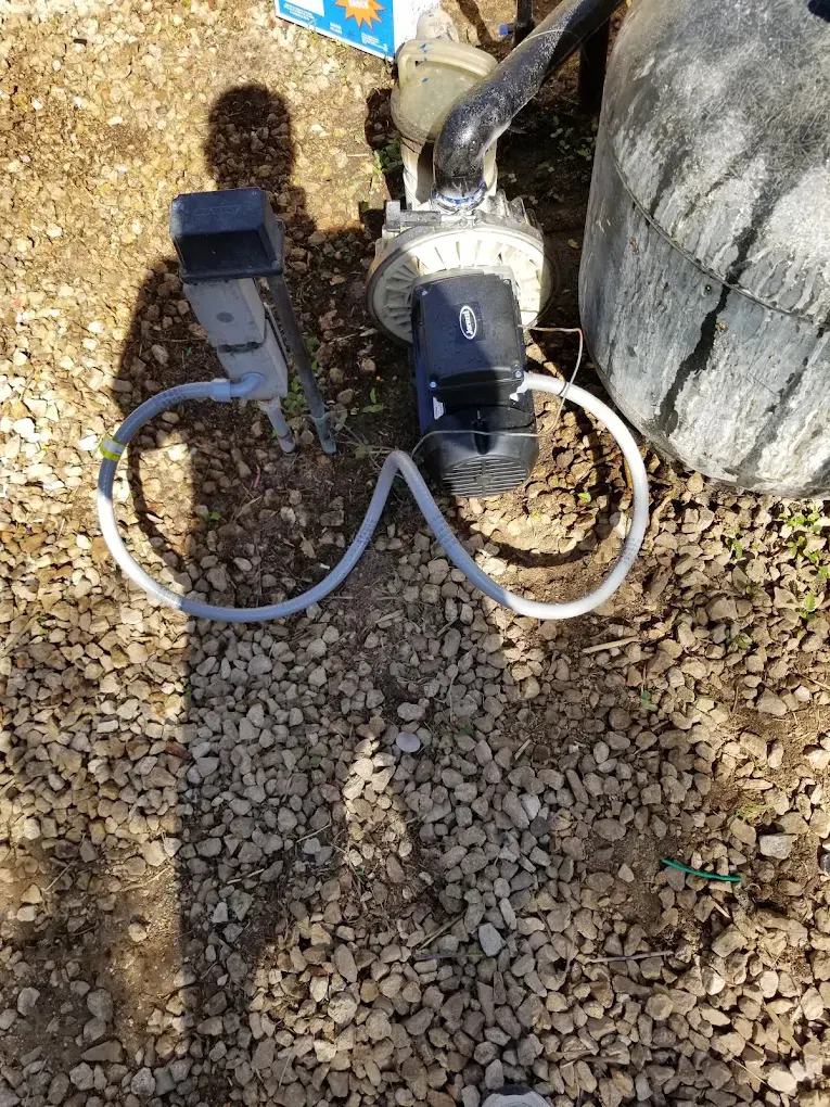 Outdoor electrical outlet and power cords on gravel ground near concrete foundation