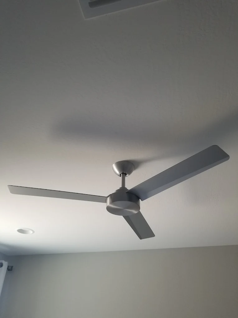 Modern brushed nickel ceiling fan mounted on white drywall ceiling